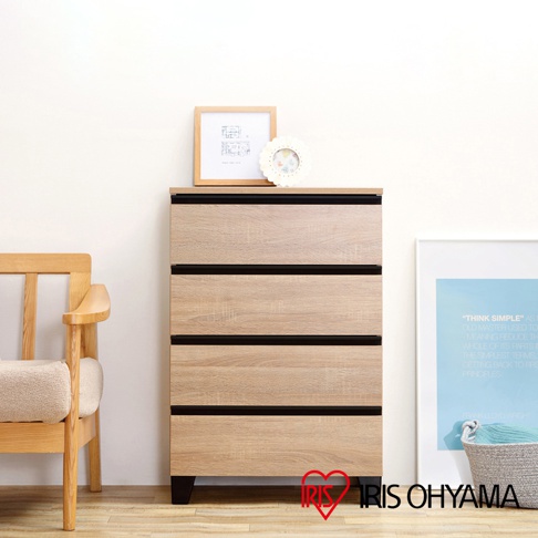 木紋五斗櫃，附黑色櫃腳，櫃面有木框畫作與裝飾品，右側有掛畫與編織籃。