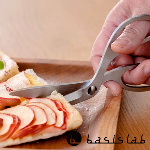 右手持用可拆式不鏽鋼萬用料理剪刀，正在切割木盤上的蘋果派。剪刀採用亮面不鏽鋼材質，握柄為人體工學設計。