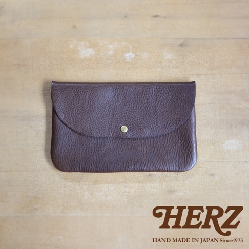 深棕色皮革製成、附有鈕扣式翻蓋的小物收納袋，材質紋理清晰，風格簡約。