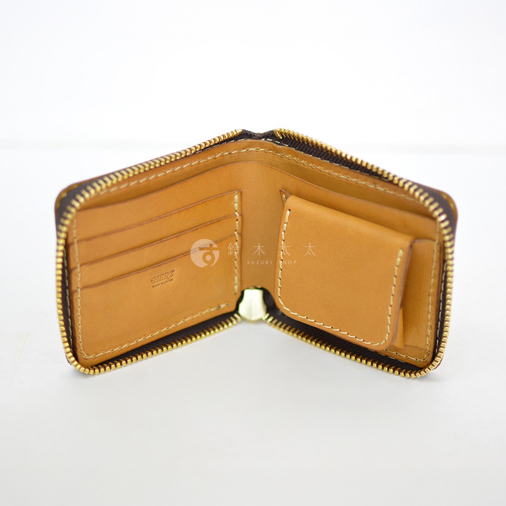 這是一款日本HERZ職人手作的淺棕色皮革拉鍊短夾，內部展示左側具備多層卡槽，右側配有實用的翻蓋零錢袋，整體呈現自然皮革質感與精緻縫線細節，並刻有HERZ品牌字樣。