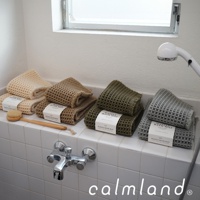 四款鬆餅紋瞬乾吸水浴墊，顏色由左至右為米白、卡其、墨綠、淺灰，皆為織物材質，表面呈現格子紋理，擺放在浴室浴缸邊緣。