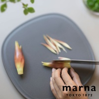 marna TOKYO 1872，一人正在使用刀具切割日式薑，砧板上還有切好的薑絲，背景有模糊的綠葉。