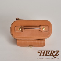 職人手作皮革軟皮相機包 N-6，呈現溫潤的淺棕色調。包體由光滑的皮革製成，頂部設有堅固的提把，並以銅扣固定。包身側面有拉鍊設計，正面有一個帶有金屬釦的翻蓋口袋。