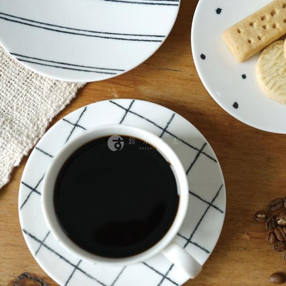 gohara mamiko 美濃燒手繪馬克杯，白色陶瓷杯身搭配黑色網格線條，杯內盛有深褐色咖啡，下方搭配同款網格線條盤。