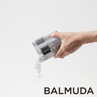 手持透明集塵盒，傾倒細碎紙屑，集塵盒帶有黑色按鈕和灰色零件，背景為白色。