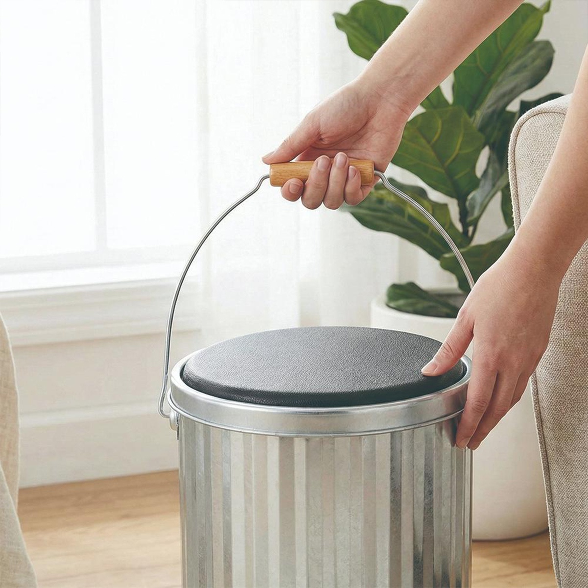 OBAKETSU手工製儲物桶，銀色鍍鋅鋼材質，頂部有黑色坐墊，附有木質手柄的提把，可兼具椅子與收納功能。