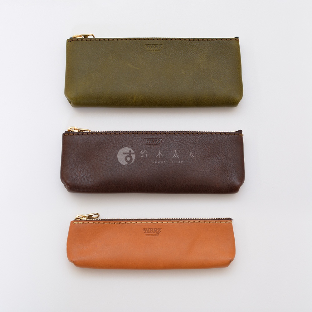 三款職人手作皮革經典收納筆袋，分別為橄欖綠、深棕色和橘棕色，皆配有金色拉鍊，材質為皮革。