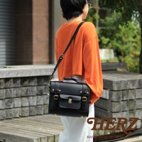 黑色皮革學院風三用迷你後背包，配有翻蓋、金屬鎖扣、皮帶扣和頂部提把，可肩背或斜背。