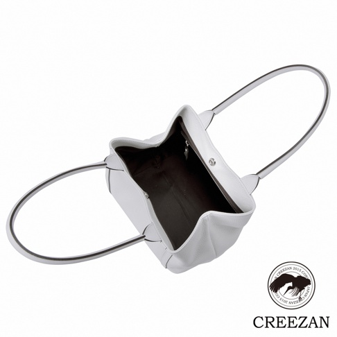 白色方形托特包，採用荔枝紋皮革材質，配有雙提把和磁扣開合，內部為深色襯裡。