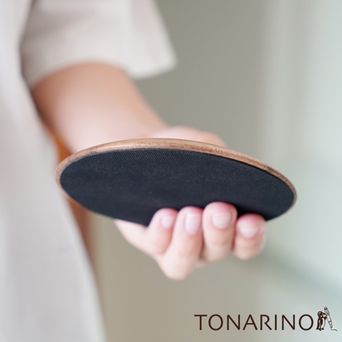 一只手托著一個圓形門擋，門擋邊緣為天然實木材質，表面為黑色防滑墊。