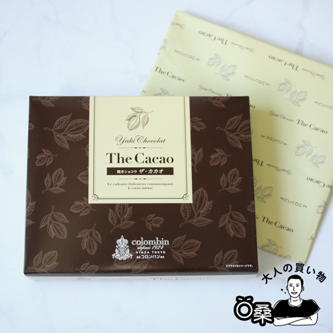 深棕色包裝盒上印有淺棕色的可可葉圖案，盒中央的米白色標籤印有「Yaki Chocolat The Cacao」字樣及可可果實圖案，下方有日文與法文說明，並有「colombin GINZA TOKYO」品牌標誌。