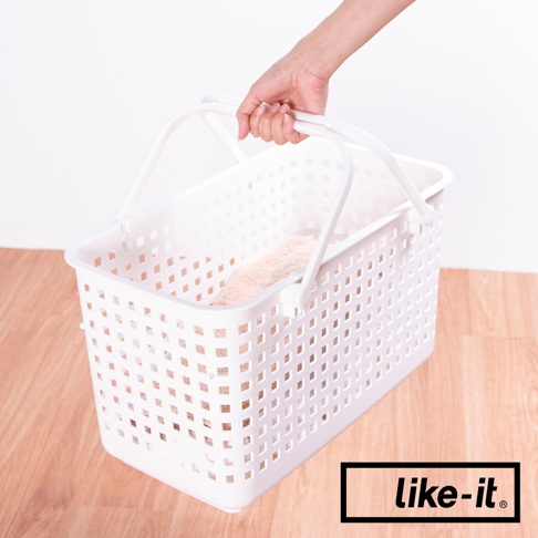 白色塑膠夾縫疊疊洗衣提籃，帶有兩個可提式把手，籃身佈滿方形鏤空孔洞，內部裝有一塊淺褐色毛巾。