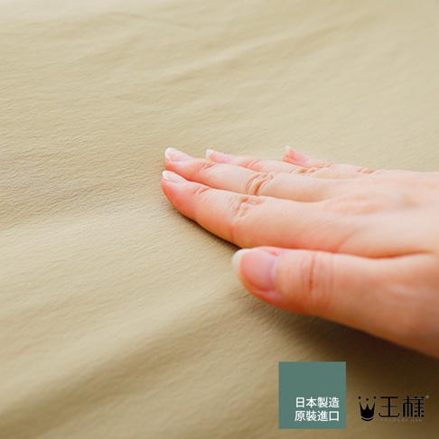 手輕柔觸碰淺卡其色紋理布料，右下方有日本製造及王樣品牌標誌