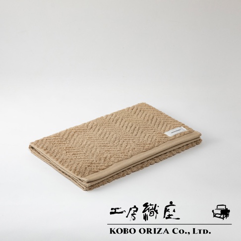 ECOR 天然系人字紋有機棉毛巾，米棕色，材質為有機棉，觸感柔軟，紋理細緻，邊緣有品牌標籤。