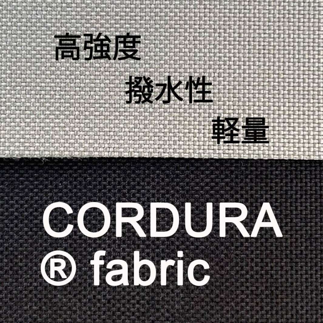 這張圖片展示了兩種不同顏色的 CORDURA 織物布料紋理，上方為淺灰色，下方為深黑色。圖片中央以白色字體標示著 CORDURA fabric 品牌名稱，上方則以日文列出該布料的三大特性：高強度、撥水性以及輕量。