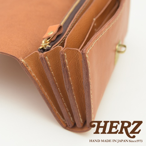 職人手作的淺棕色皮革長夾，展現多卡層的風琴式設計，搭配黃銅拉鍊與扣環，質感細膩。