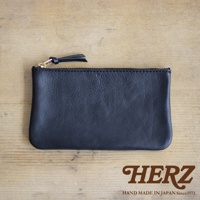 黑色皮革拉鍊式小物收納袋，配有金色拉鍊和皮革拉頭，置於木質紋理背景上。