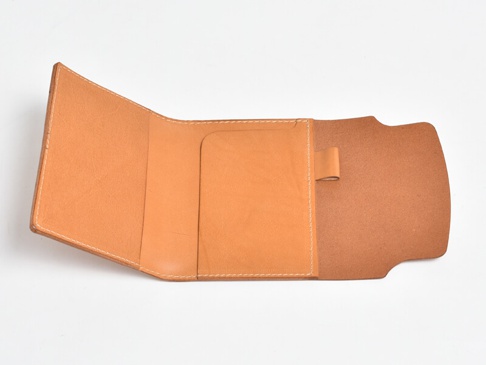 職人手作皮革A6記事本書套，天然皮革材質，呈現溫潤的淺棕色調。內側設有卡片夾層與筆插，邊緣車縫線整齊。