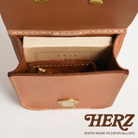 職人手作皮革經典腰袋E-49，淺棕色皮革，袋內裝有書籍和小錢包，整體線條簡潔，搭配黃銅釦件。