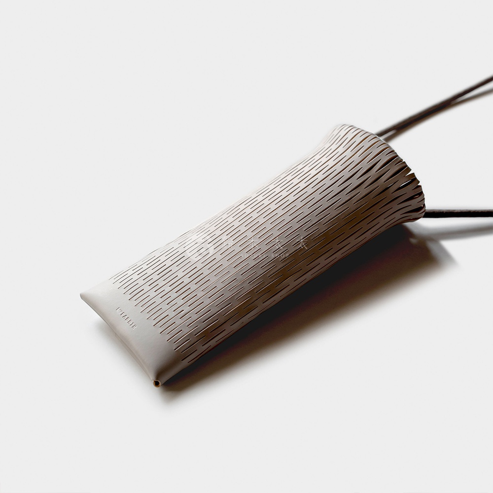 FABRIK 皮革隨形貼合伸縮小包，帶有細緻的斜紋鏤空設計，附有掛繩