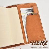 職人手作皮革手帳書套，淺棕色皮革，內有卡片夾層，壓印有HERZ品牌標誌與日文製造資訊。