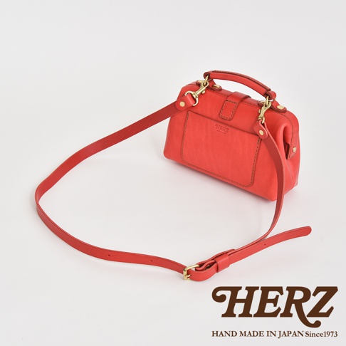 紅色職人手作迷你軟皮杜勒斯包，以皮革製成，設有可調節的肩帶和金色金屬扣環，包身印有品牌標誌。