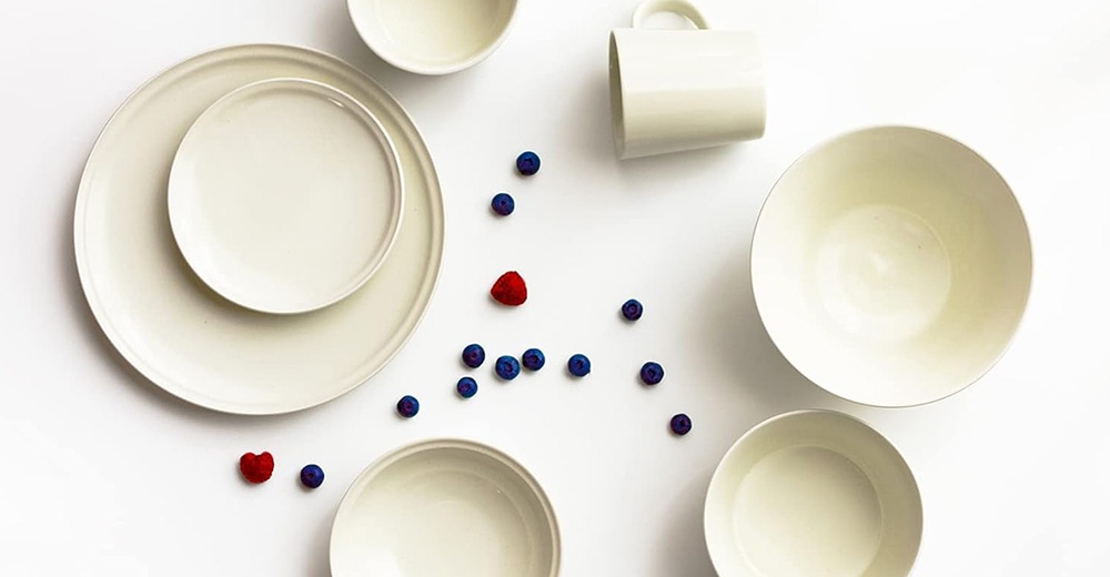 Ciel 美濃燒淺碗和盤子，共有三種柔和釉彩，包括淺米色、淺灰色和淺藍色，搭配一個白色馬克杯，散佈著藍莓和覆盆子。