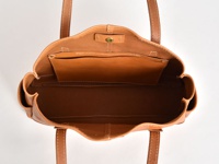 職人手作皮革橫式肩背托特包，呈現自然棕色調，採用真皮材質。包款內部有開放式隔層，外觀有簡約縫線設計，搭配雙肩帶。