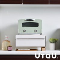 抽屜式收納整理櫃，白色，配有銀色把手，上方堆疊綠色烤箱。櫃子下方放置木質托盤，托盤上有餐巾，旁邊有果醬罐和一袋吐司。