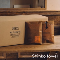 Pile Crafts 素面極簡風客製化毛巾，產品包裝為牛皮紙袋，其中一個有橘色標籤，標示「ORANGE」，材質標示為「COTTON 100%」。