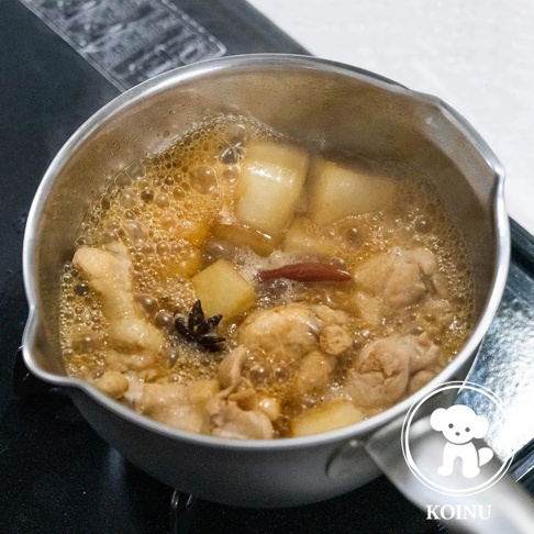 不鏽鋼雪平鍋內有雞肉塊、塊狀食材、肉桂棒和八角，鍋中湯汁滾沸冒泡。