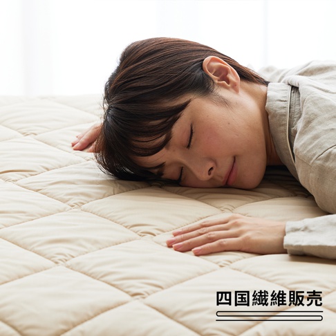 一女子側臥於米白色菱格紋鋪棉床墊上，床墊材質柔軟，呈現舒適的睡眠氛圍。