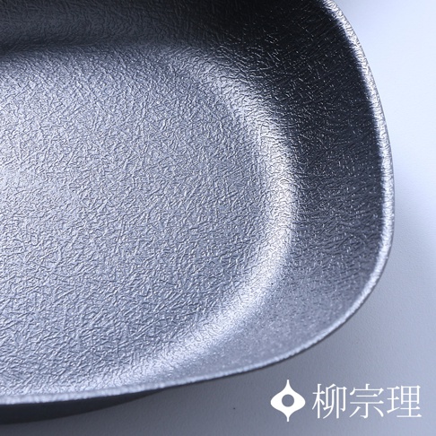 特寫俯拍柳宗理雙網紋單手鐵鍋的內部鍋底，顯示出金屬材質上獨特且細密的交錯紋理，右下角印有柳宗理的品牌標誌。