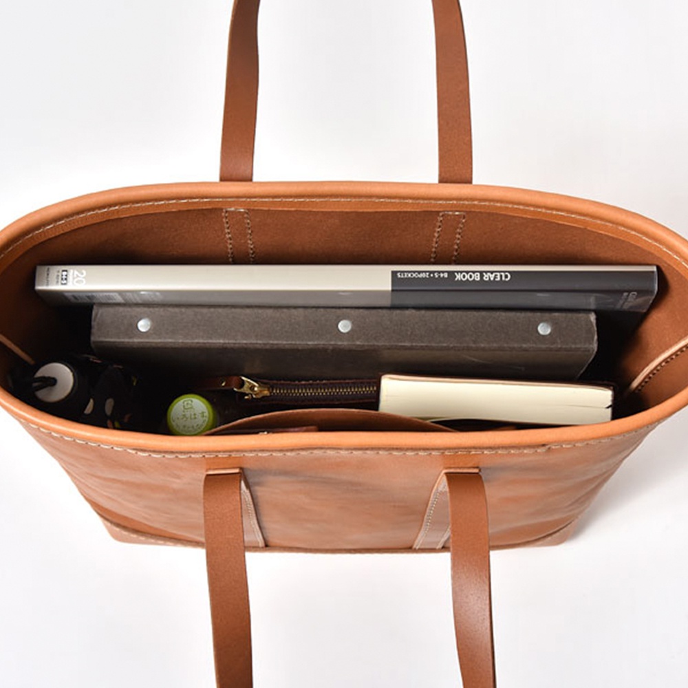 棕色皮革托特包，內部裝有文件夾、書籍、雨傘和筆記本。