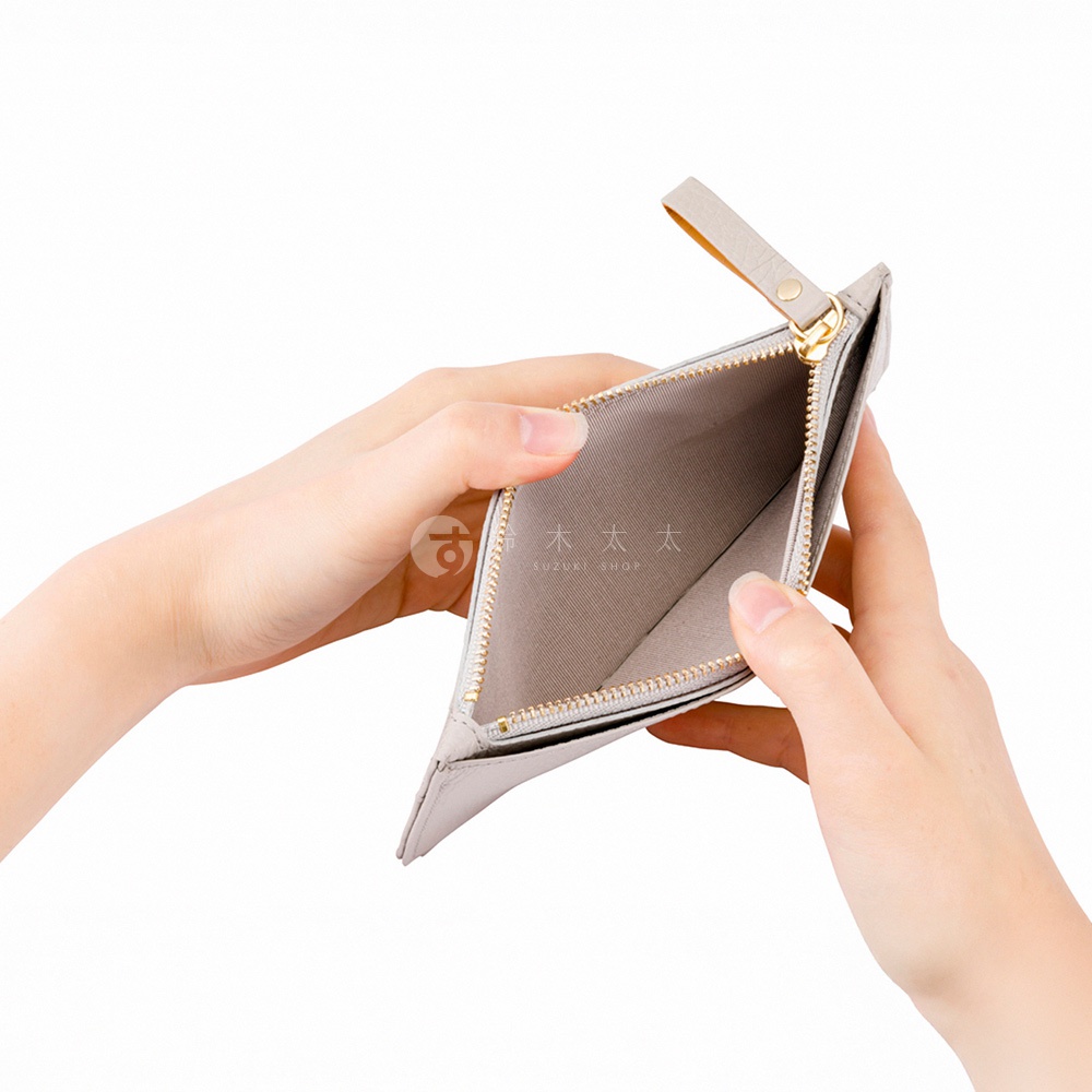 一雙手正拿著一個淺灰色拉鍊長夾，夾子拉開露出內部，夾子內側印有「木木」和「SUZUKI SHOP」的標誌。