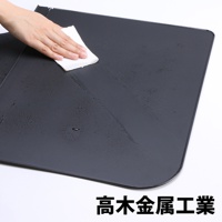 深灰色 L 型折疊擋油板，表面有水珠，一隻手正用白色紙巾擦拭。