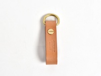 職人手作皮革吊掛扣帶，淺棕色天然皮革，附有黃銅D形環和螺絲固定，皮革上壓印有「HERZ」品牌標誌及「MADE IN JAPAN」字樣。