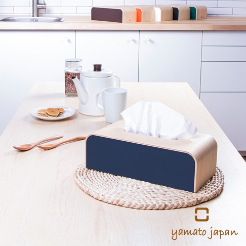手作布藝木質面紙盒，木質盒身搭配深藍色布藝飾面，盒內露出白色面紙，置於編織墊上，背景為廚房檯面及白色櫥櫃。