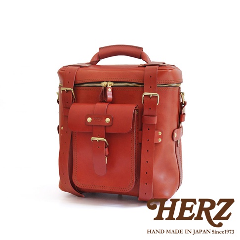 職人手作皮革大型三用旅行後背包，採用紅色皮革製成，設有頂部提把、拉鍊主袋、前方翻蓋口袋，並配有可調節的皮革肩帶和金屬扣環。