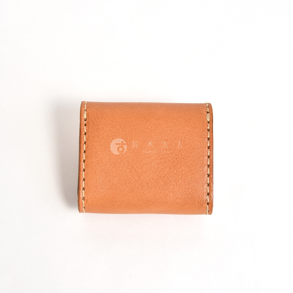 這是一款日本HERZ職人手作的棕色皮革雙折收納零錢包，表面帶有自然皮革紋理與細緻的縫線設計，呈現簡約且耐用的質感，外觀刻有鈴木太太品牌標誌。