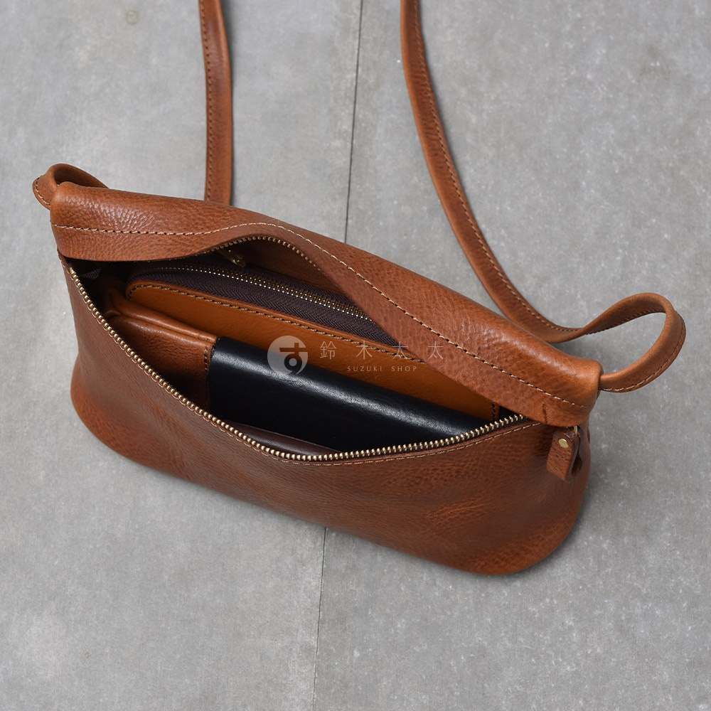 職人手作皮革Organ貼身斜背包，M尺寸，焦糖棕色，內有錢包、卡夾與手機等物品。