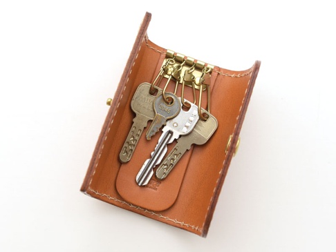 職人手作的經典鑰匙包，採用光滑的棕色皮革製成，內有四個金屬鑰匙鉤，用於懸掛鑰匙。