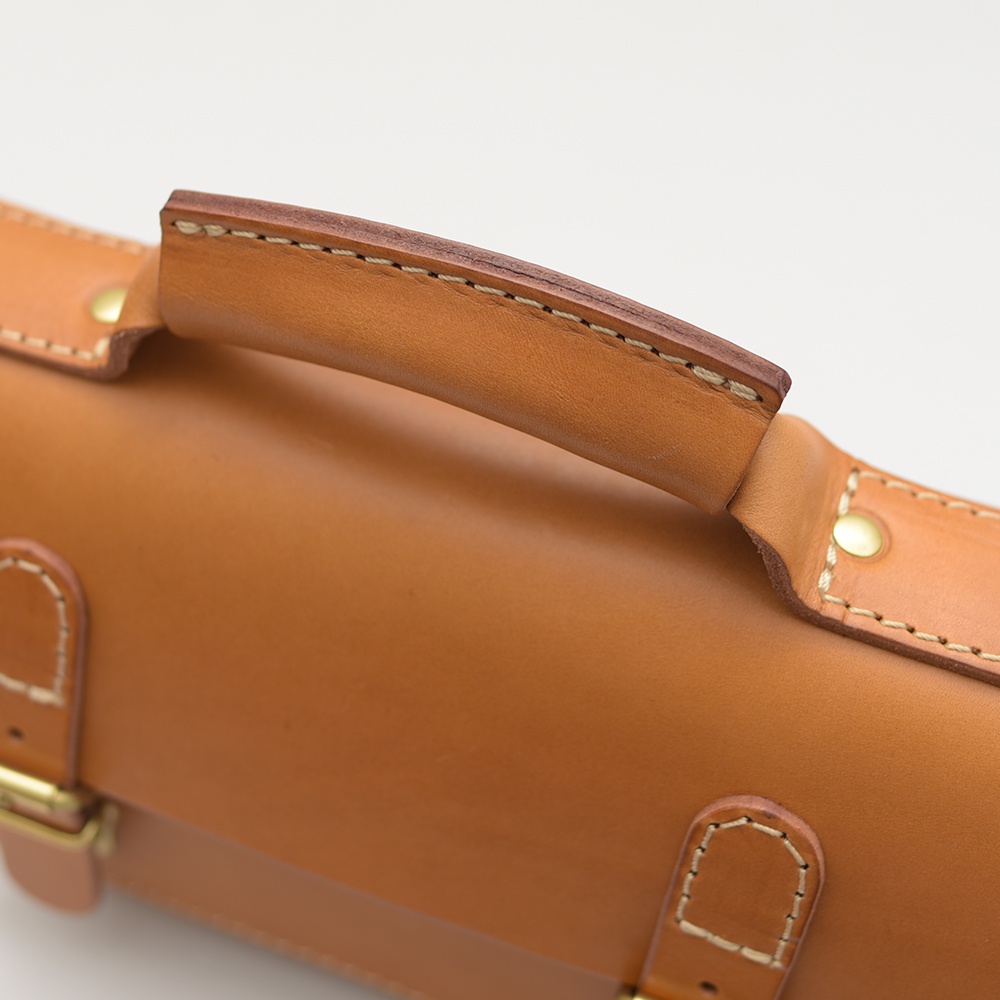 職人手作皮革雙扣兩用迷你肩背包 CW-67，展示提把細節，淺棕色皮革，搭配米色縫線與金色金屬扣環。