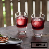 兩個透明玻璃杯中各裝有紅酒和冰球，冰球呈現圓形。杯子放置在深色木桌上，背景為模糊的木柵欄和綠色植物。