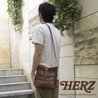 職人手作皮革輕便單肩側背包，採用鞣製皮革製成，顏色為溫暖的棕色調。包身設計簡約，配有翻蓋式開口及金屬釦，外側有方形貼袋，適合日常攜帶。