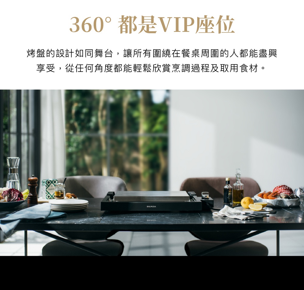 The Plate Pro 極致電烤盤 (黑色)，設於餐桌中央，烤盤表面為銀灰色金屬材質，機身為黑色。旁邊擺放著食材、餐具與調味料。