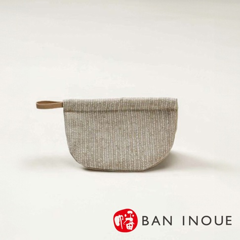 Tricot 棉麻防燙鍋套，淺米色，織紋表面，帶有同色系縫線與一個淺棕色皮革提把，半圓形設計。