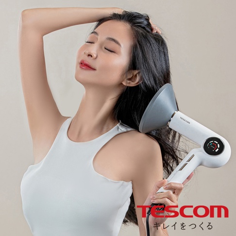 一位女性正在使用白色 Tescom 離子吹風機吹乾頭髮，吹風機的集風罩貼近她的頭髮。
