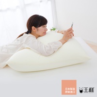 一位女性側臥在淡黃色的巨大枕頭上，枕頭材質看起來柔軟，女性穿著白色長袖上衣，手持手機。