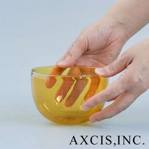 一隻手捧著琥珀色透明玻璃製的復古圓潤點心碗，碗內有手指的倒影。